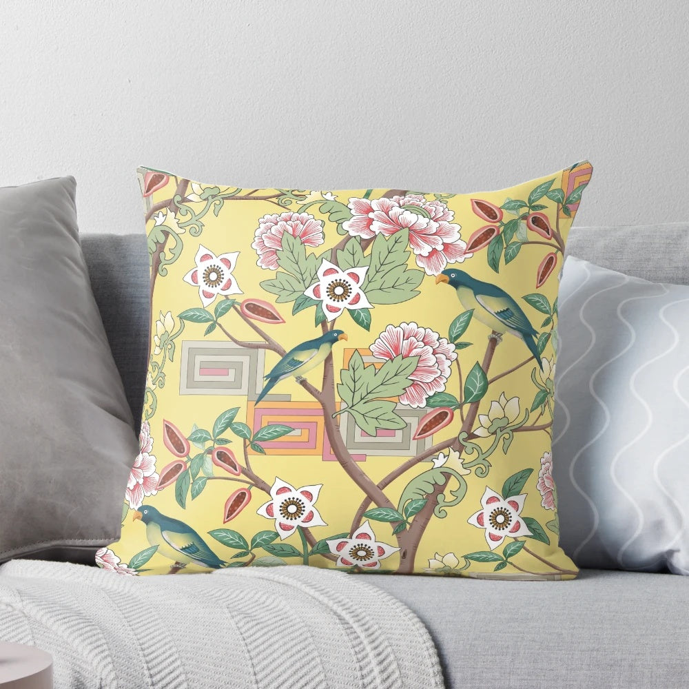 A beautiful decorative pillow featuring a chinoiserie-inspired design with vibrant parrots and peonies on a butter yellow background.
