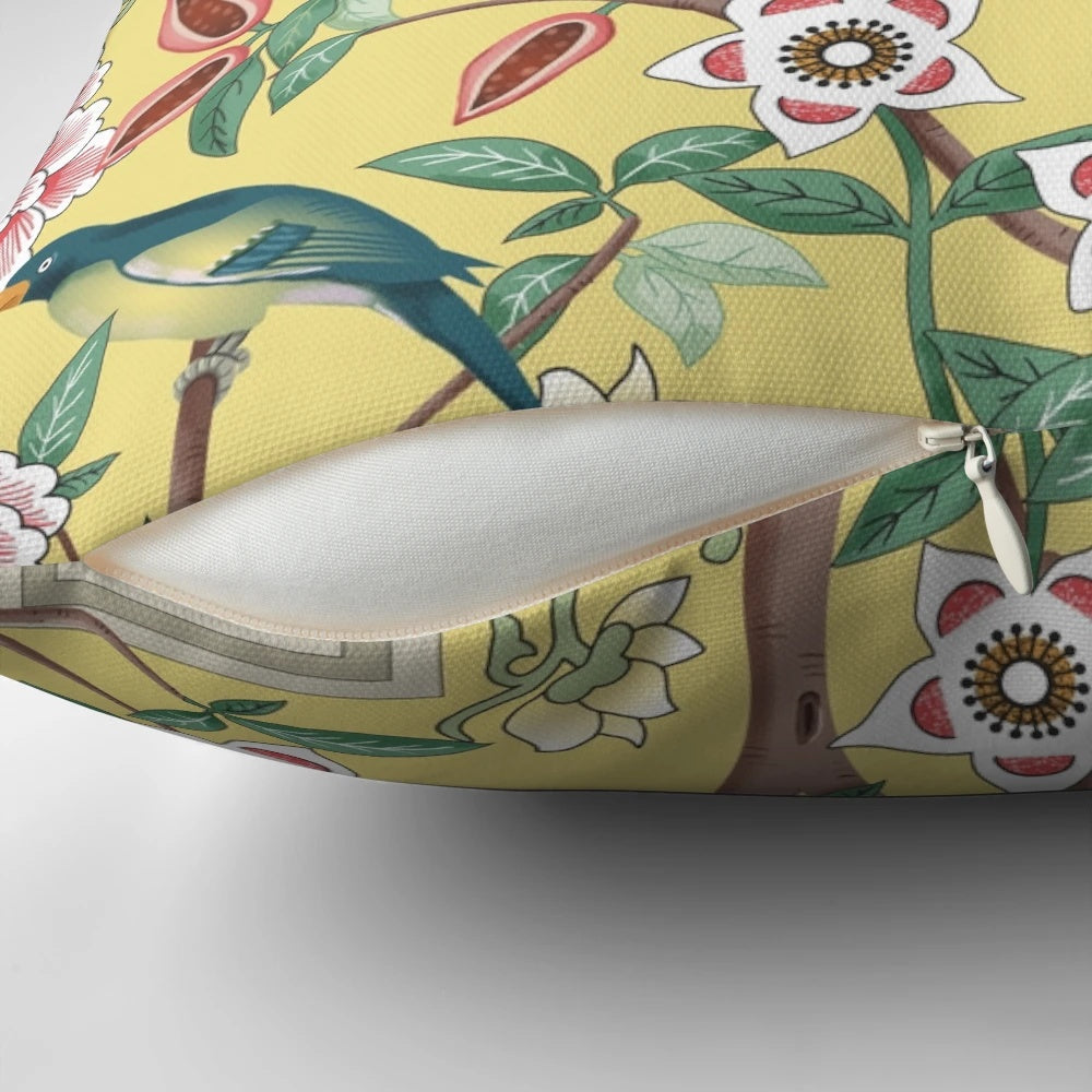 A beautiful decorative pillow featuring a chinoiserie-inspired design with vibrant parrots and peonies on a butter yellow background.