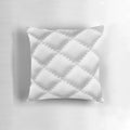 Closeup of a white, quilted leather-effect pillow with a plush, textured surface.