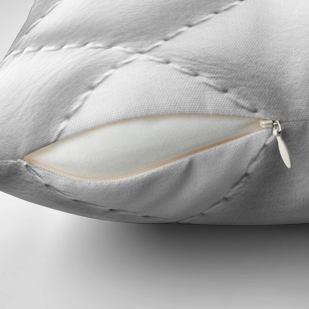 Closeup of a white, quilted leather-effect pillow with a plush, textured surface.