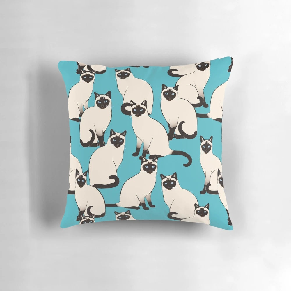 Decorative pillow featuring an elegant pattern of Siamese cats with blue eyes on a turquoise background