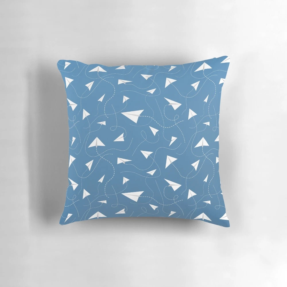 A soft, colorful pillow featuring a paper plane pattern against a blue sky background.
