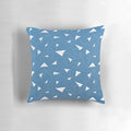 A soft, colorful pillow featuring a paper plane pattern against a blue sky background.