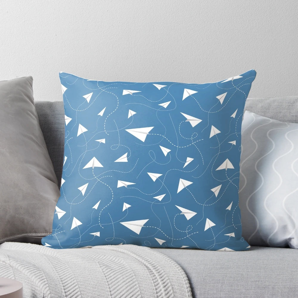 A soft, colorful pillow featuring a paper plane pattern against a blue sky background.