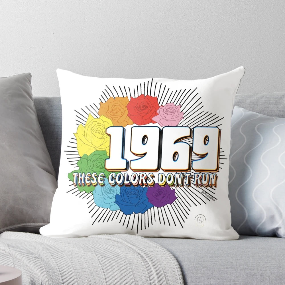 Colorful pillow with text "These Colors Don't Run" against a diverse background, representing inclusivity and social justice.