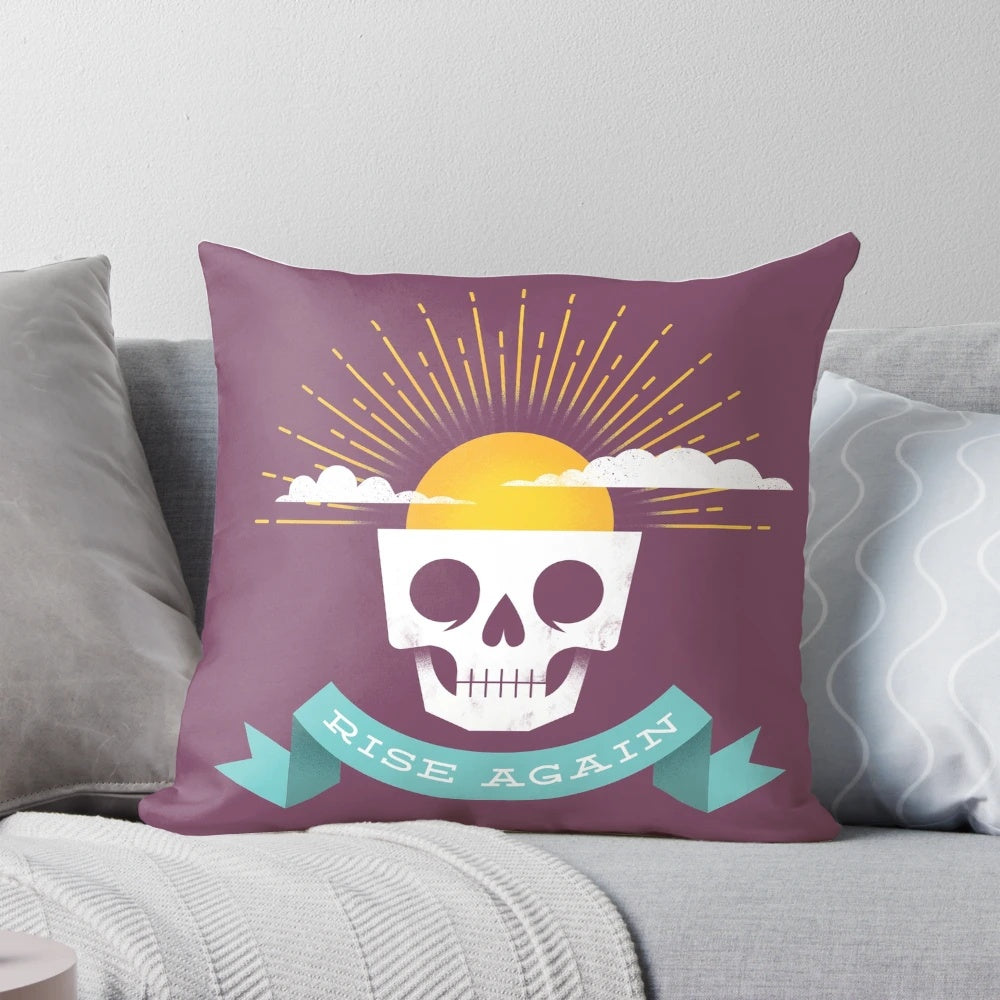 Rise Again Pillow featuring a sun rising over a skull, symbolizing new life and optimism.