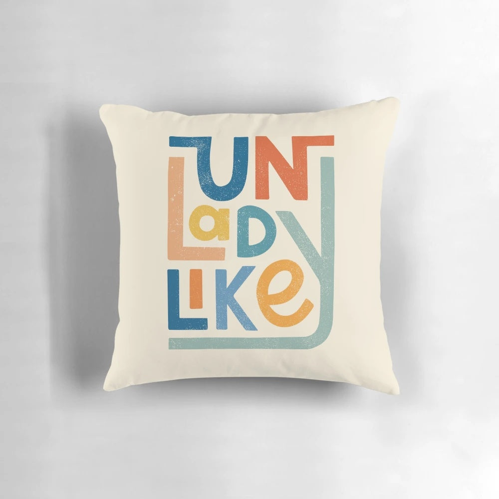 Vibrant UNLADYLIKE graphic design pillow featuring bold lettering and a feminist message.