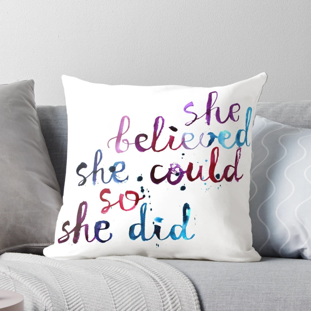 Decorative pillow with the motivational quote "She believed she could so she did" in calligraphic typography and watercolor design.