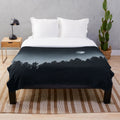 Plush blanket featuring a forest scene with trees, moonlight, and a dark night sky