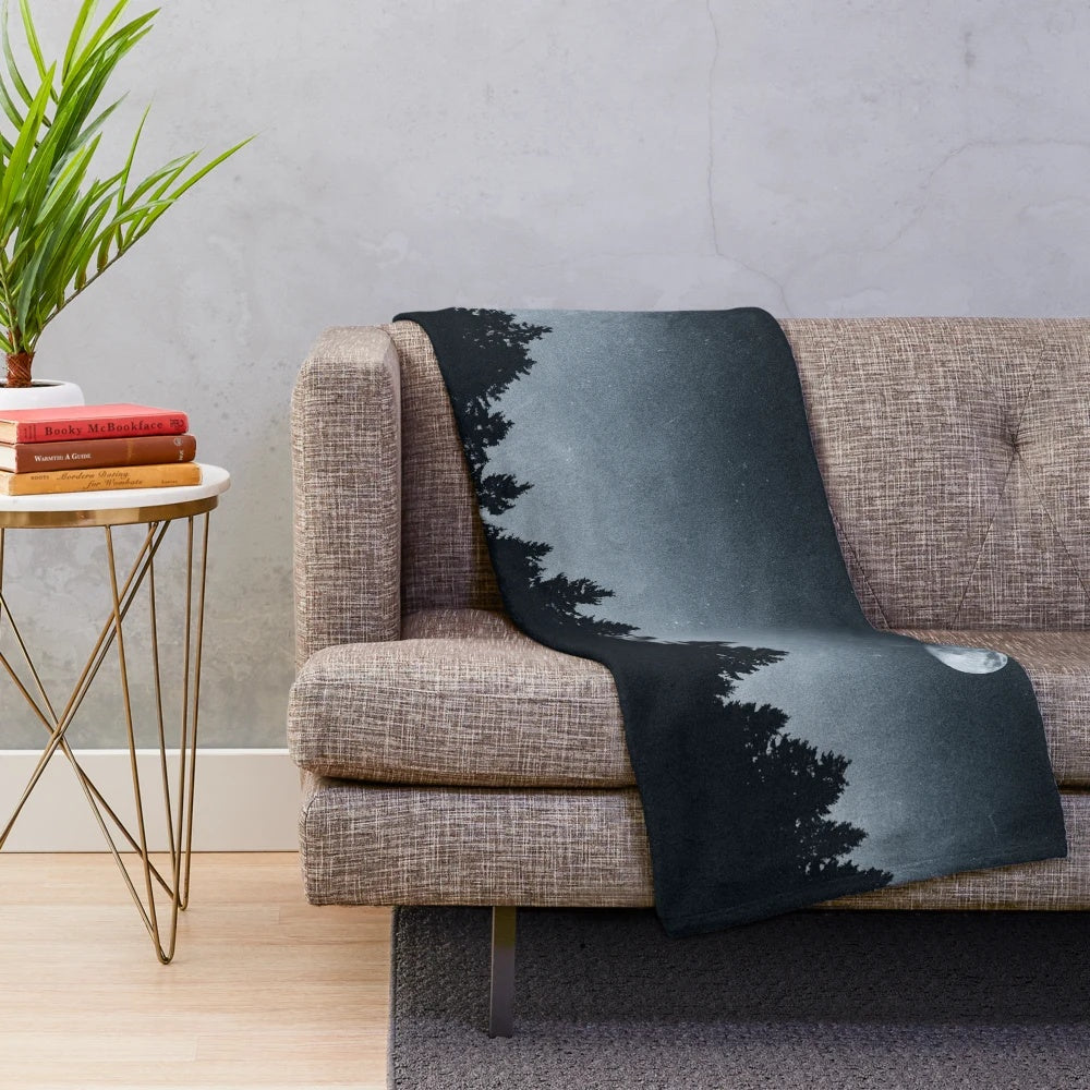 Plush blanket featuring a forest scene with trees, moonlight, and a dark night sky
