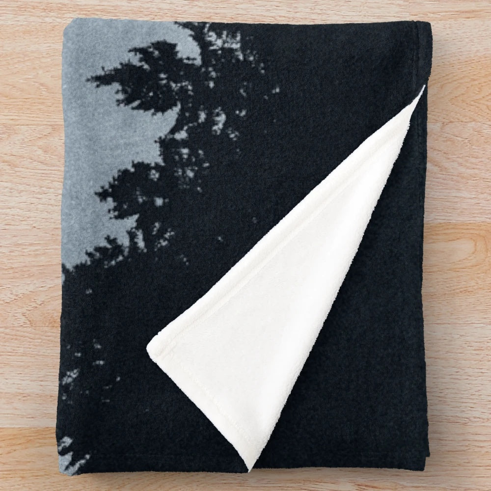 Plush blanket featuring a forest scene with trees, moonlight, and a dark night sky
