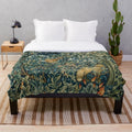 Plush blanket featuring a blue green floral tapestry design with forest animals like pheasant and fox