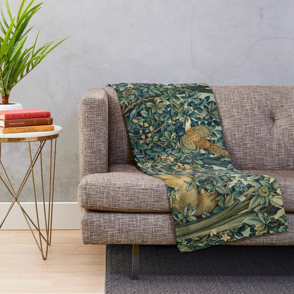 Plush blanket featuring a blue green floral tapestry design with forest animals like pheasant and fox