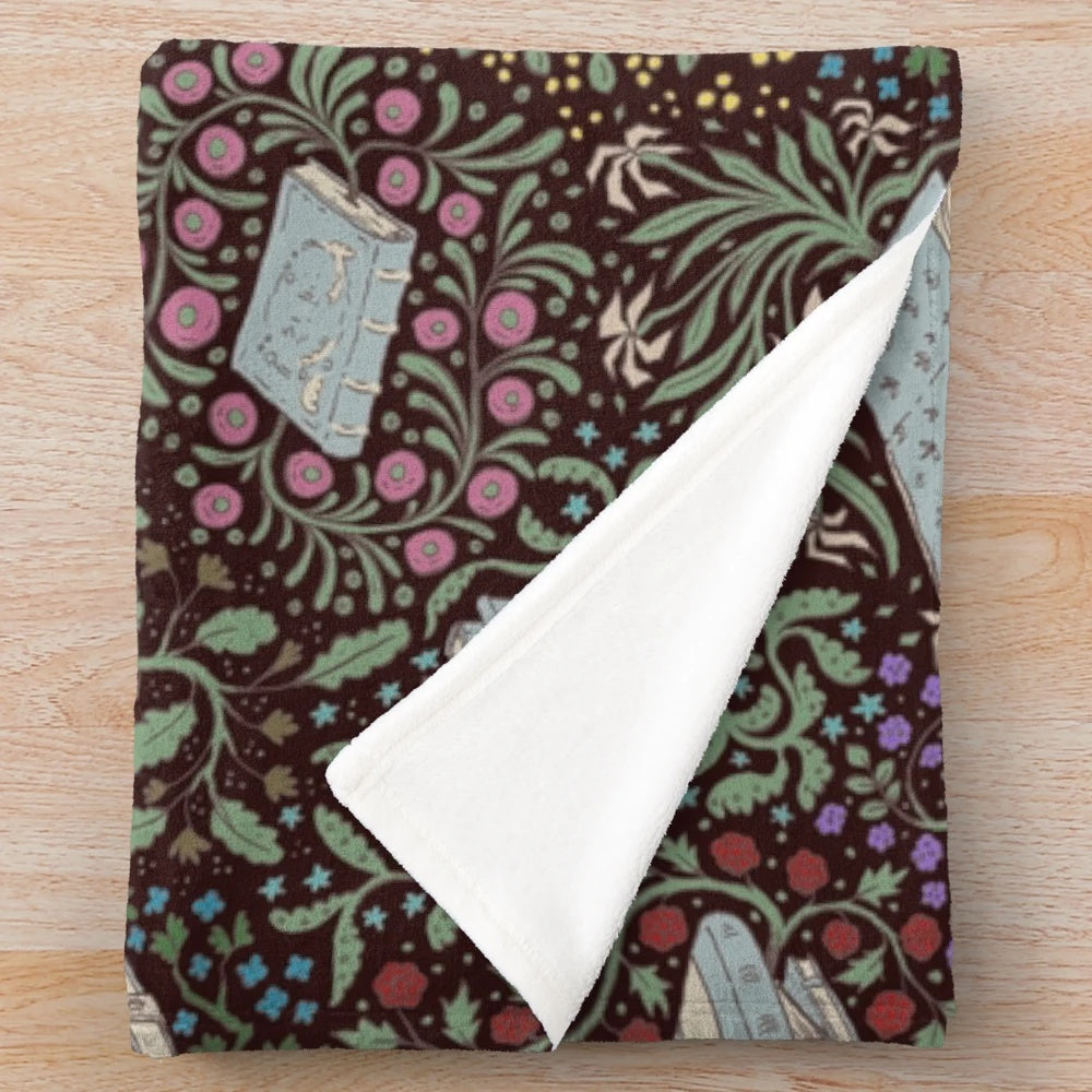 Soft and cozy plush blanket featuring a whimsical design of books and flowers in a fantasy woodland setting