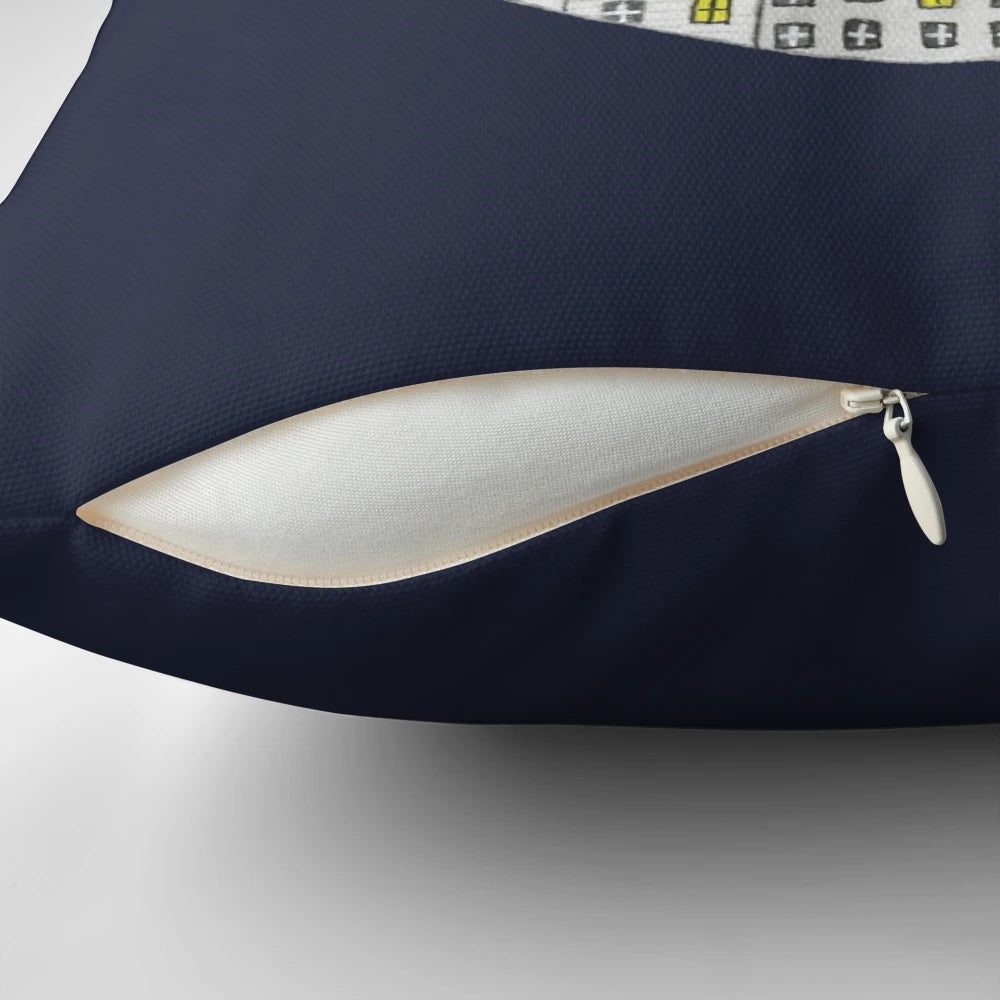 Cozy pillow featuring a whimsical cat in a night town scene with the moon, stars, and houses.