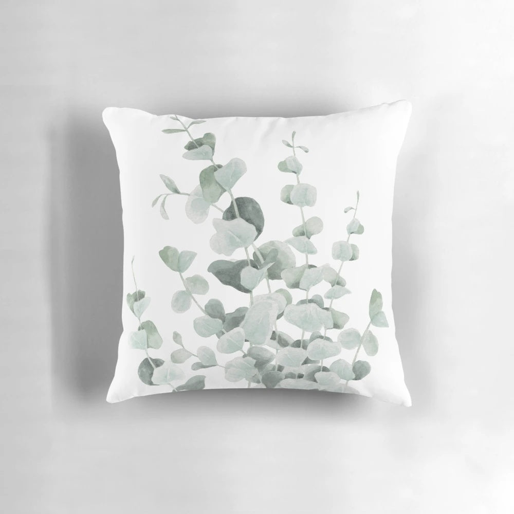 A decorative pillow featuring a watercolor illustration of standing eucalyptus leaves in shades of teal and sage.