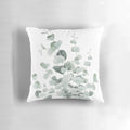 A decorative pillow featuring a watercolor illustration of standing eucalyptus leaves in shades of teal and sage.