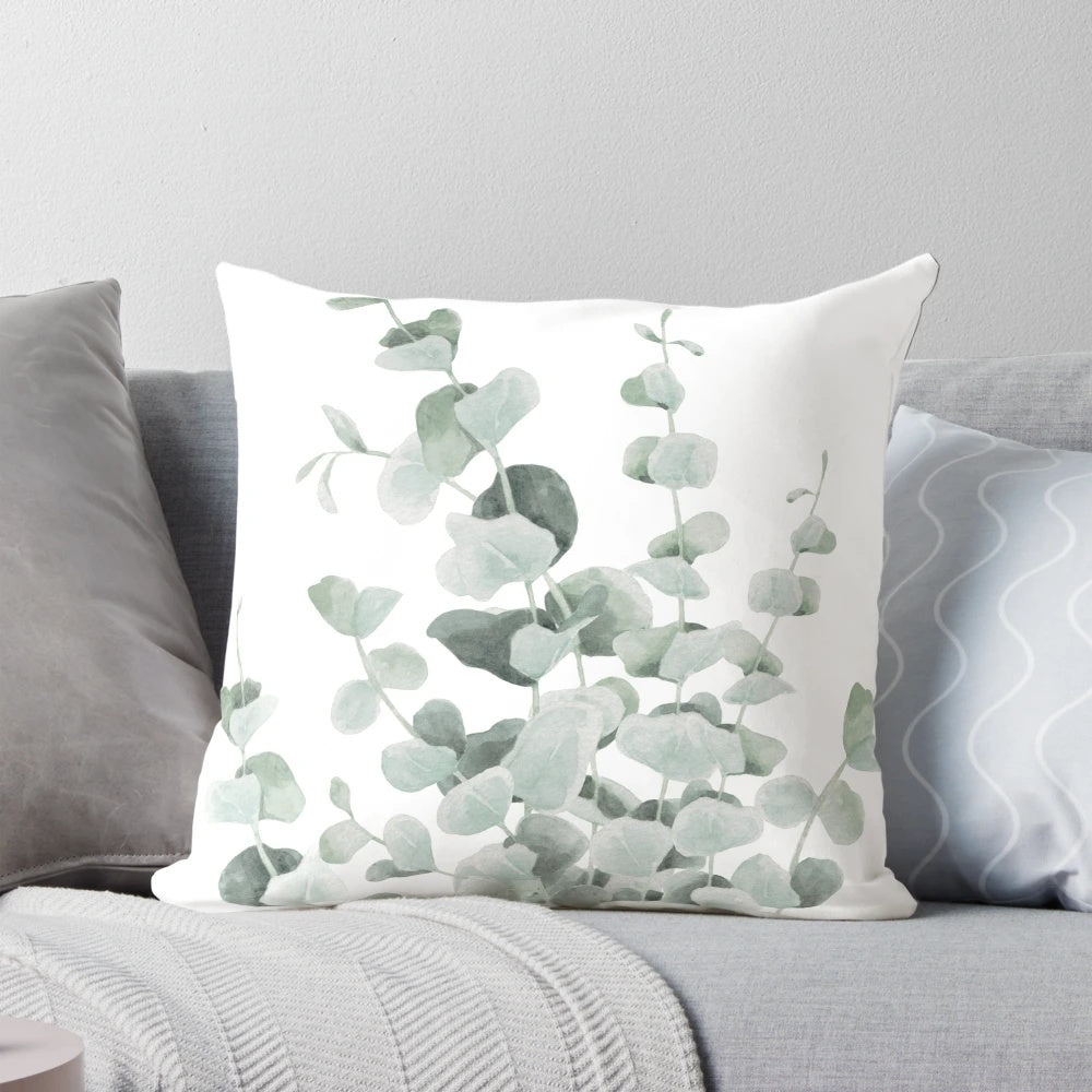 A decorative pillow featuring a watercolor illustration of standing eucalyptus leaves in shades of teal and sage.
