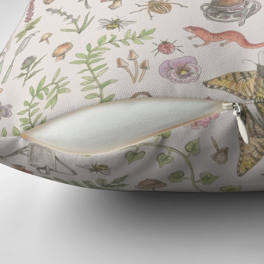 A soft, faded pink pillow with a delicate cottagecore pattern featuring whimsical florals, mushrooms, and magical creatures.