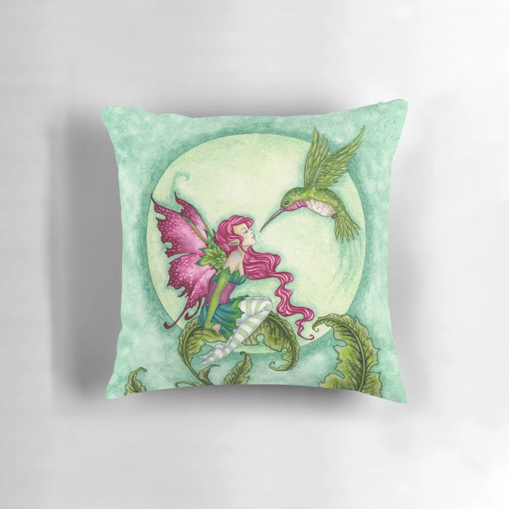 Whimsical fairy pillow featuring a hummingbird design by artist Amy Brown in shades of pink and green.