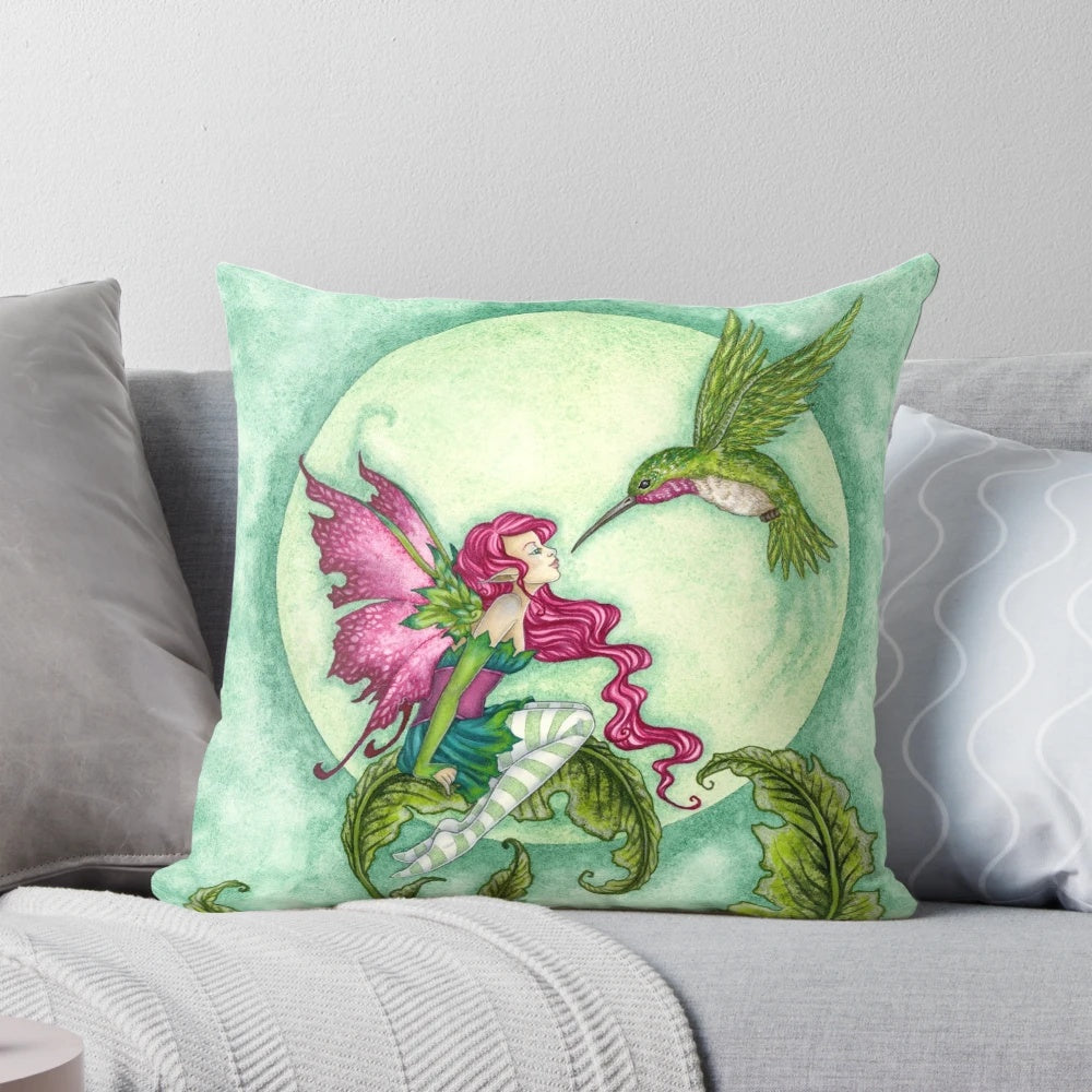 Whimsical fairy pillow featuring a hummingbird design by artist Amy Brown in shades of pink and green.