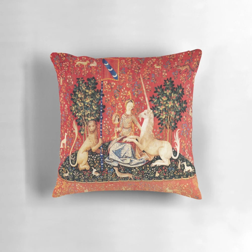 Decorative throw pillow featuring a fantasy unicorn surrounded by red, green, and blue flowers in a classic medieval art style