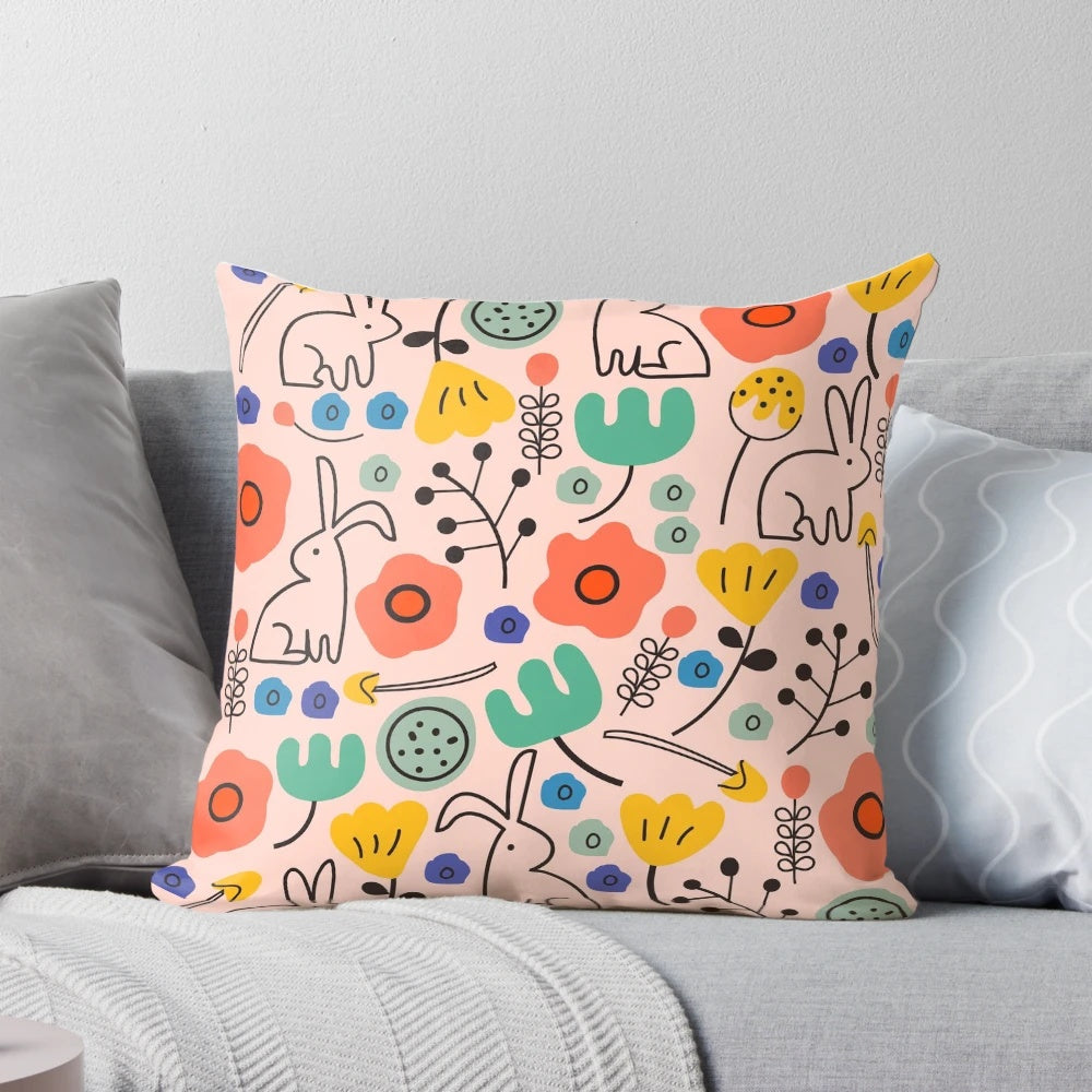 Soft, pink floral pillow with bunnies and leaves, perfect for garden-inspired home decor