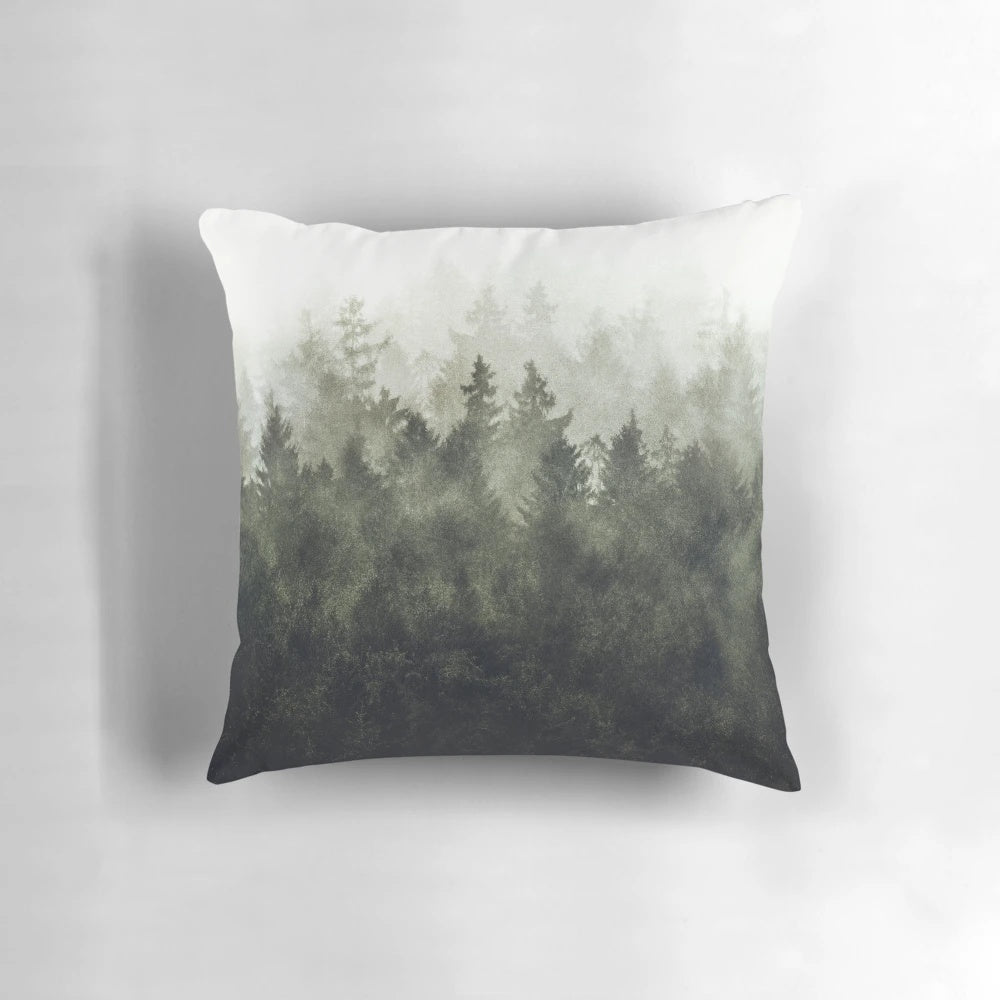 A cozy pillow featuring a dreamy, moody forest landscape with trees covered in magical fog, evoking a sense of tranquility and adventure.