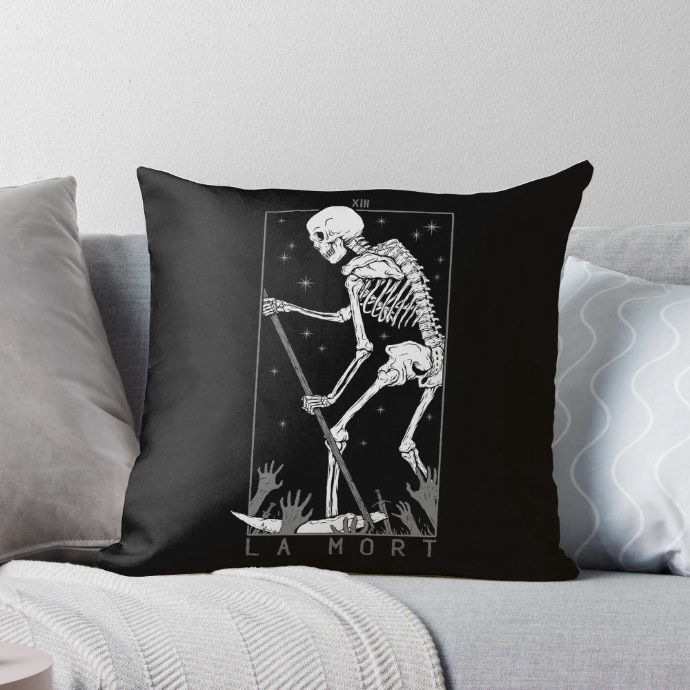 A black and white pillow featuring a macabre skull and tarot card imagery for a gothic, occult-inspired home.