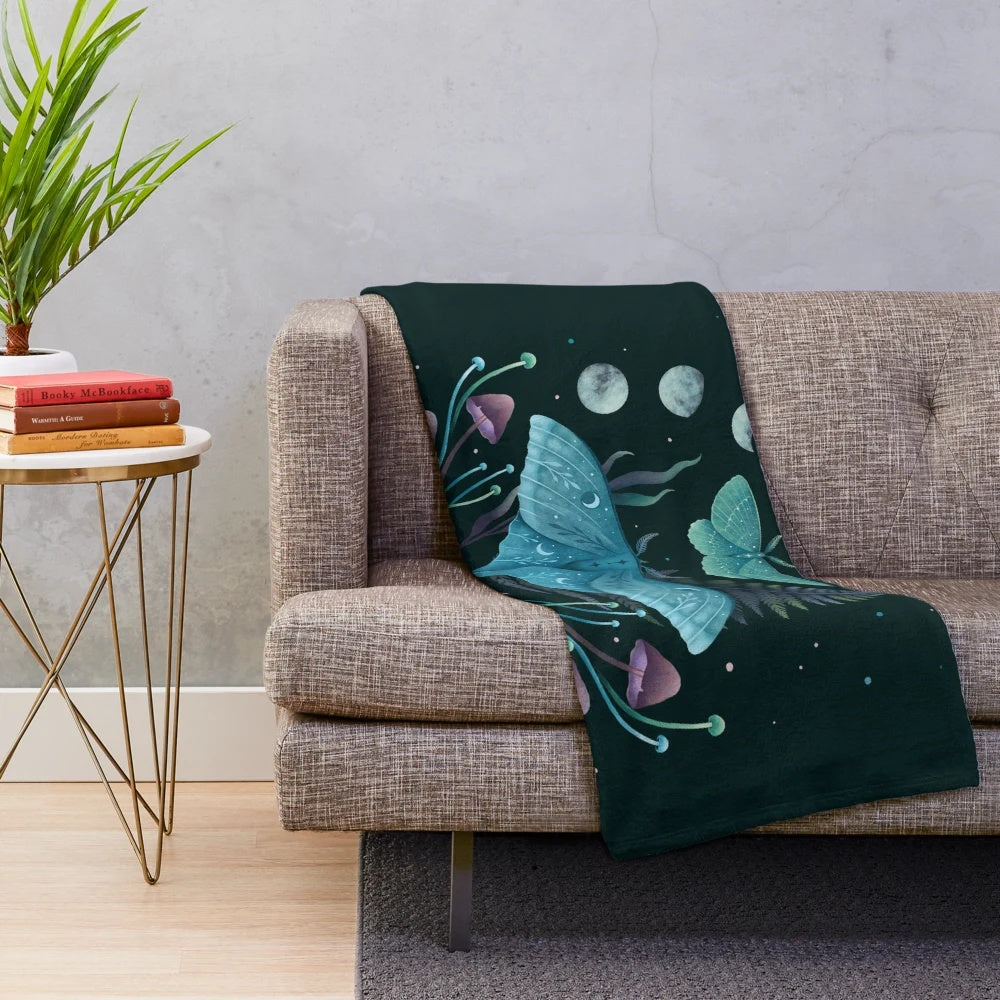 Plush blanket featuring a luna moth and emerald moth design in a botanical, night garden scene