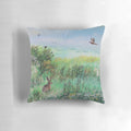 A beautiful pillow featuring a serene meadow landscape with hares and wildlife, designed by artist Jo Grundy.