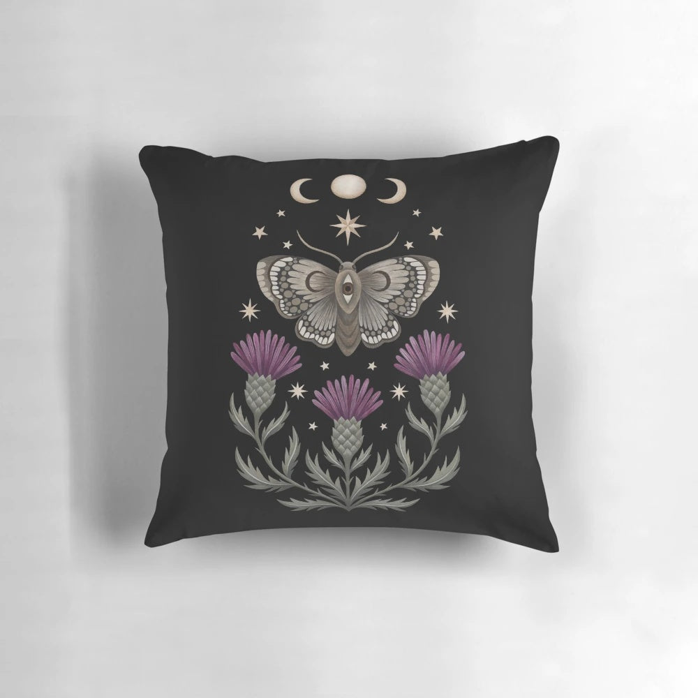 Decorative pillow featuring a moth and thistle design against a crescent moon backdrop
