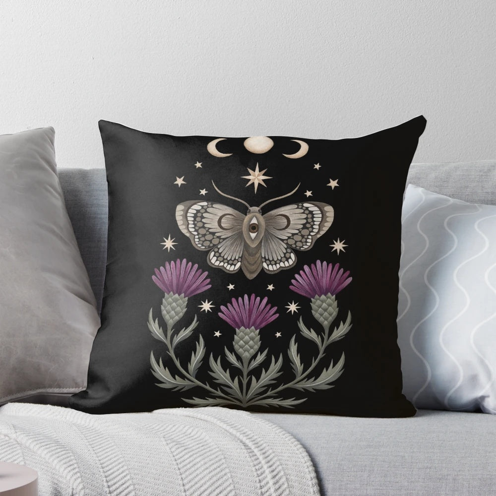 Decorative pillow featuring a moth and thistle design against a crescent moon backdrop