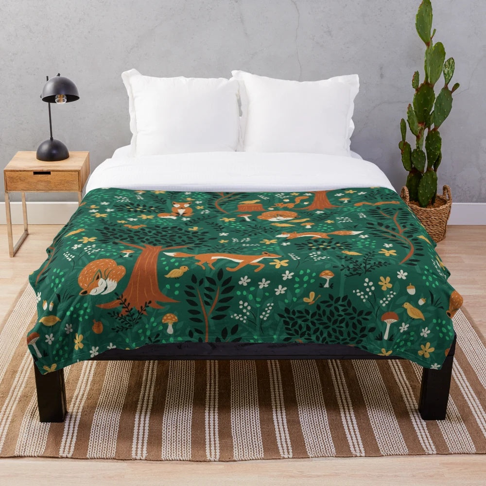 Plush blanket featuring whimsical design of foxes playing in an emerald green forest