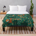 Plush blanket featuring whimsical design of foxes playing in an emerald green forest