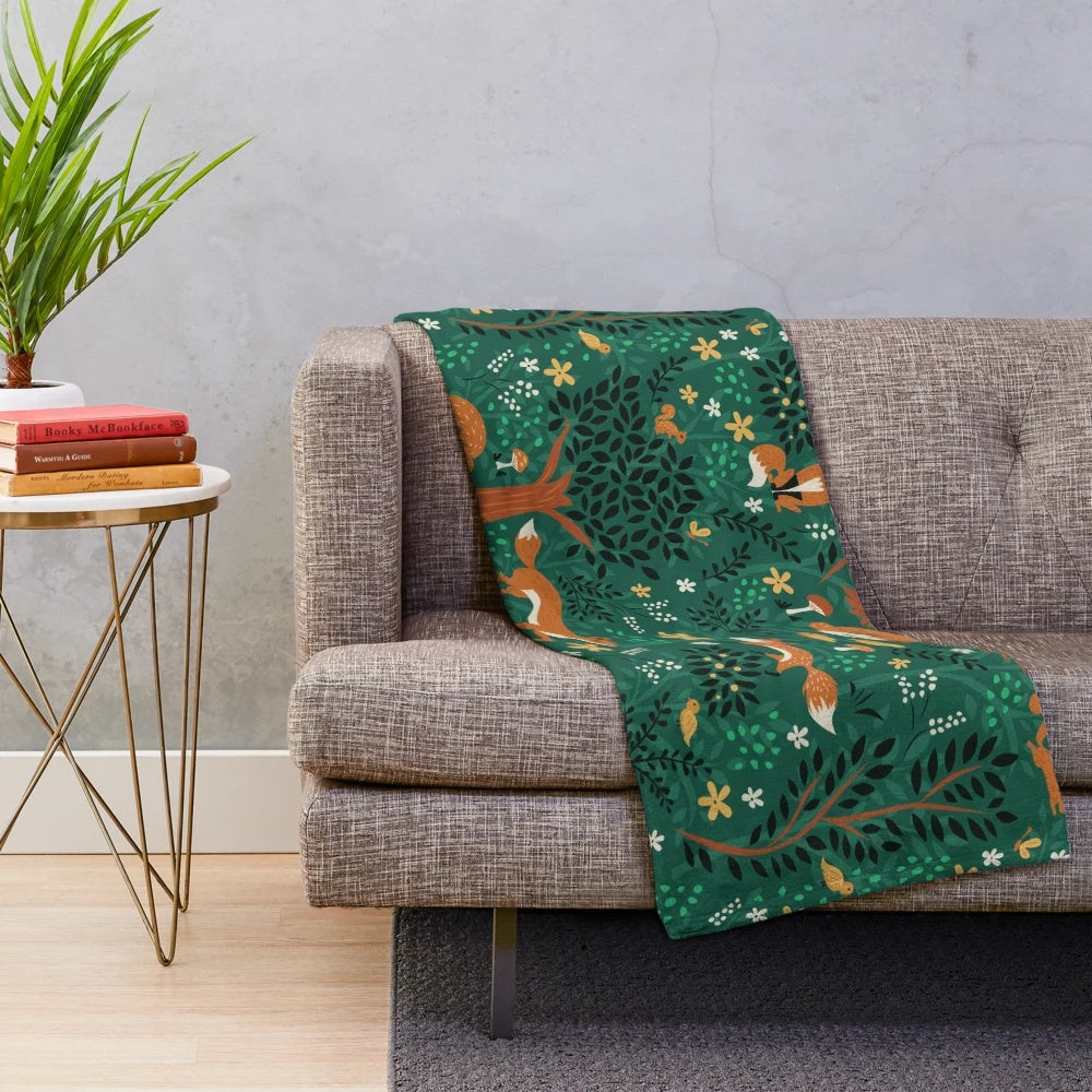 Plush blanket featuring whimsical design of foxes playing in an emerald green forest