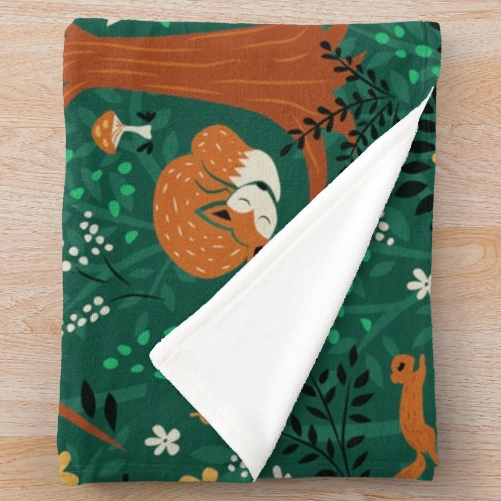 Plush blanket featuring whimsical design of foxes playing in an emerald green forest