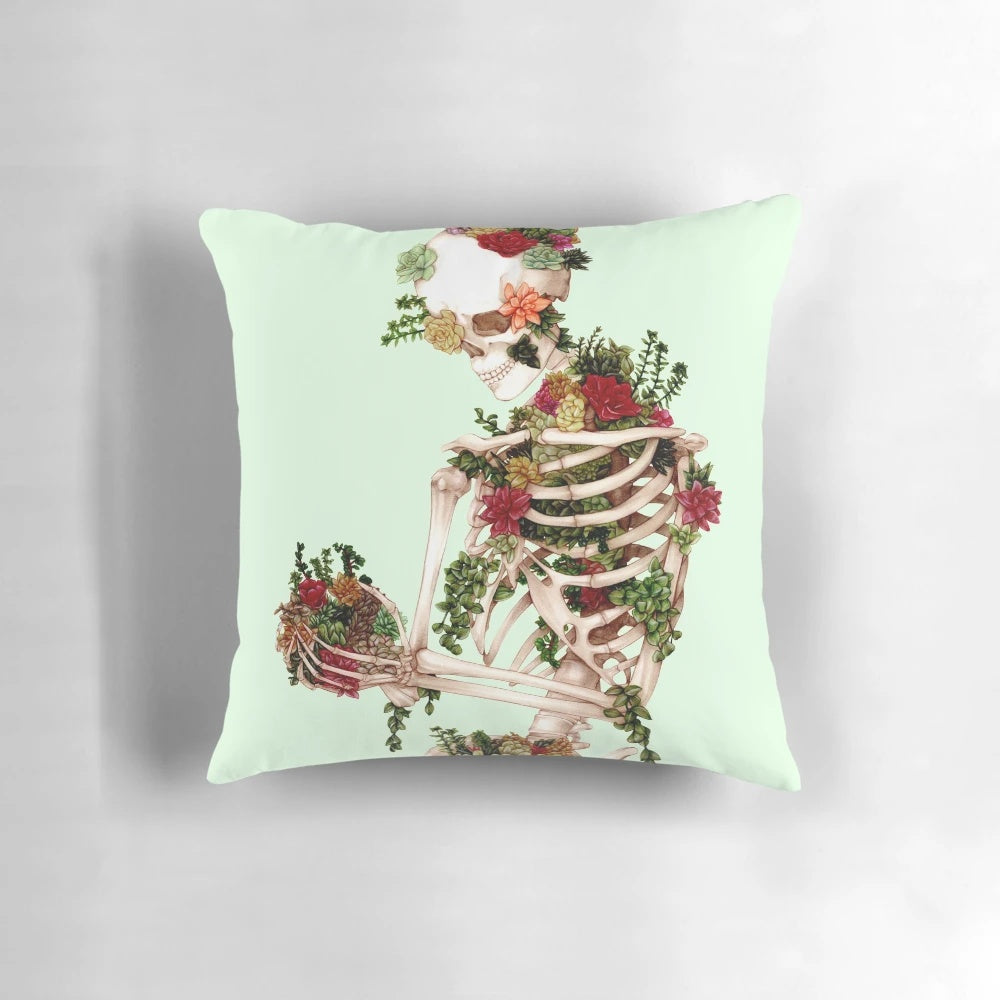 A decorative throw pillow featuring a design of a skeleton with succulents and botanical elements.