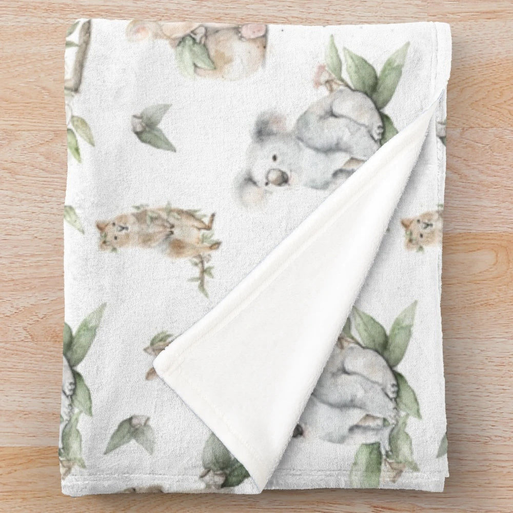 Watercolor-style illustration of Australian animals including a kangaroo, quokka, koala, and wombat on a soft, plush blanket