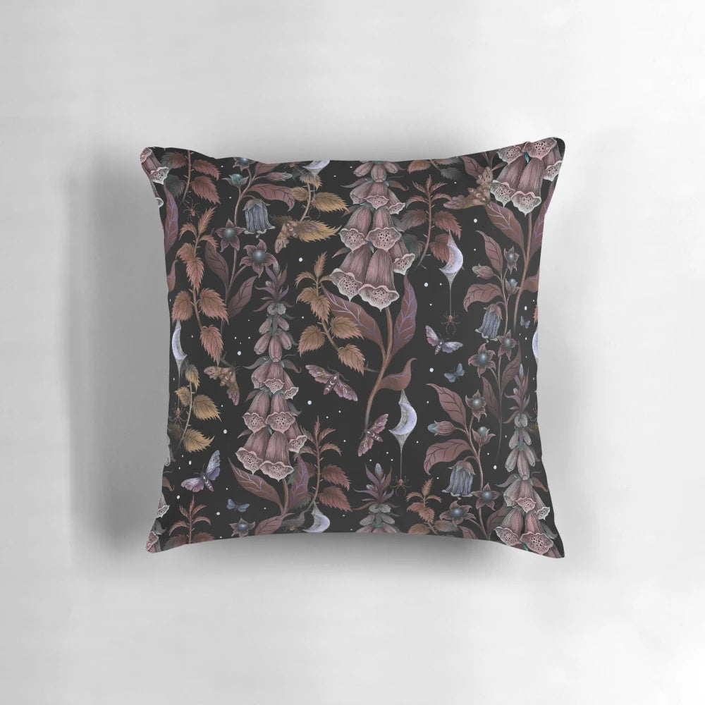 A black and white throw pillow featuring a spooky witch's garden design with a crescent moon, spider web, and haunting gothic elements.