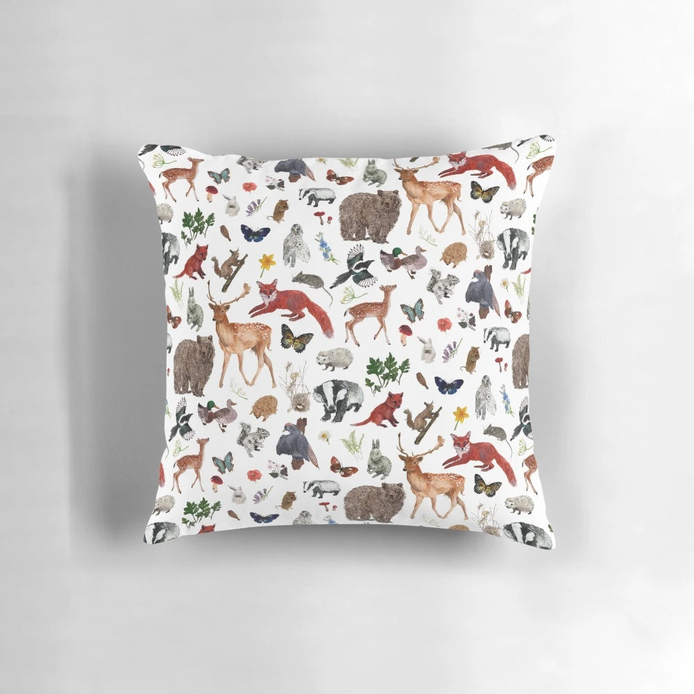 Closeup of a decorative throw pillow featuring various woodland animals like bears, foxes, and deer in a forest scene.