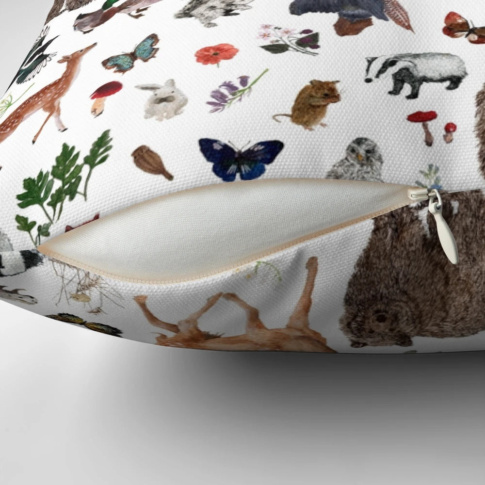 Closeup of a decorative throw pillow featuring various woodland animals like bears, foxes, and deer in a forest scene.