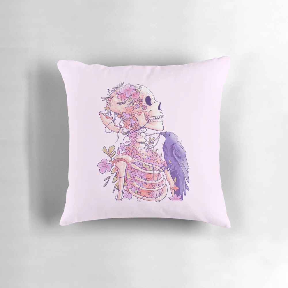 Closeup of a pastel skull-shaped pillow adorned with delicate, ethereal flowers against a dark, nature-inspired background.