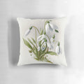 A decorative pillow featuring delicate white snowdrop flowers, a symbol of spring.