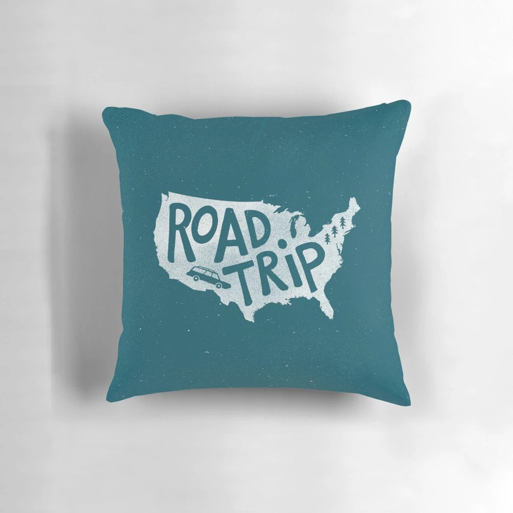 A blue, minimalist illustration pillow with the text "Road Trip USA" on it