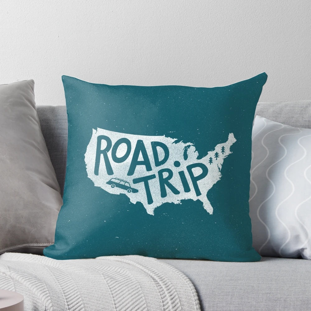 A blue, minimalist illustration pillow with the text "Road Trip USA" on it