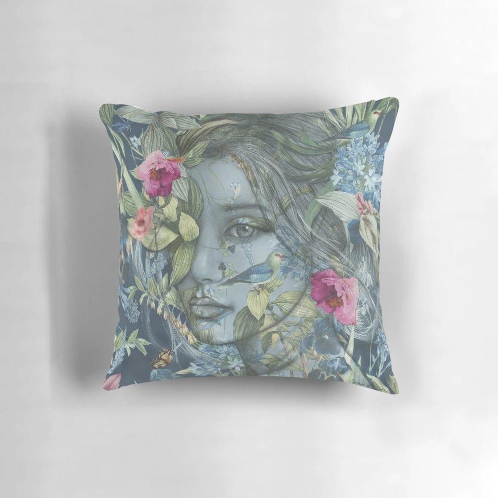 Decorative floral pillow featuring a feminine portrait of women surrounded by botanicals, birds, and flowers in pink and blue hues.