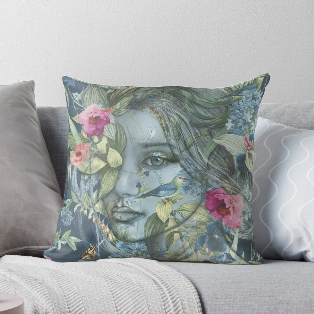 Decorative floral pillow featuring a feminine portrait of women surrounded by botanicals, birds, and flowers in pink and blue hues.