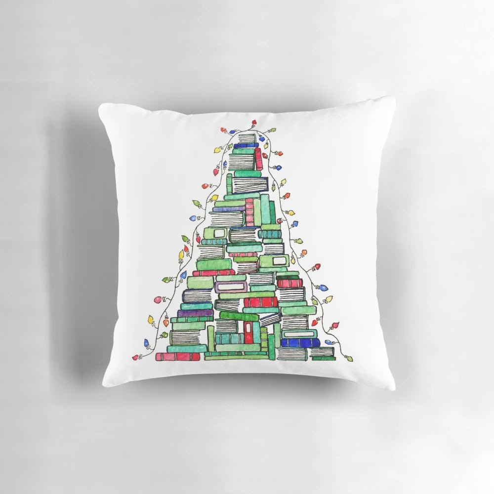 A decorative pillow featuring a stack of books arranged in the shape of a Christmas tree, perfect for book lovers during the winter holidays.