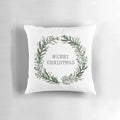 A simple, merry Christmas-themed throw pillow with a watercolor wreath design on a green background.